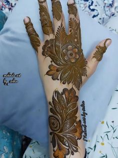 a woman's hand with henna on it and flowers painted on the palm