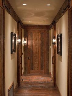 an empty hallway with wood paneling and two lights on either side of the door