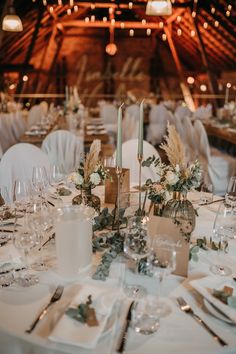 the table is set with white linens, silverware and tall centerpieces