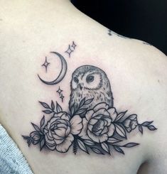 an owl and flowers tattoo on the back of a woman's shoulder