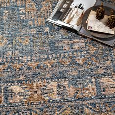 a blue and beige rug with an ornate design on the bottom, next to a magazine