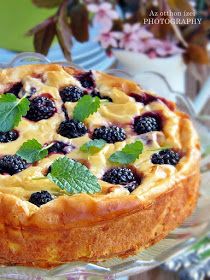 a cake with berries and cream on top is sitting on a glass platter next to flowers