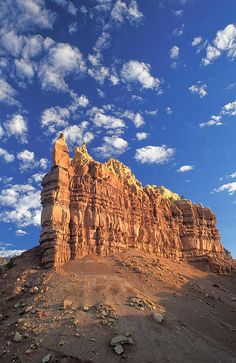 a rock formation in the desert under a blue sky with white puffy cirrle clouds