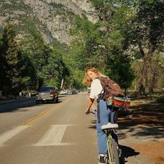 a person riding a bike on the side of a road with mountains in the background