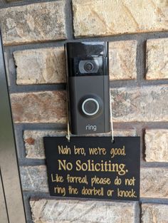 a sign attached to the side of a brick wall that says no soliciting, like formal please do not ring the door bell or knock