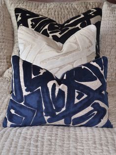 two blue and white pillows sitting on top of a bed