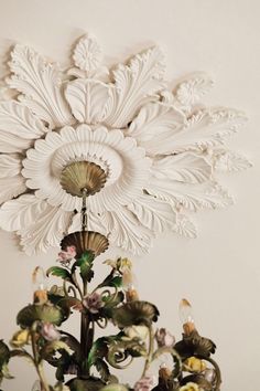 a vase with flowers on top of it in front of a white wall and ceiling