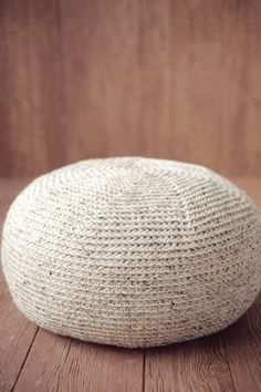 a white knitted cushion sitting on top of a wooden floor