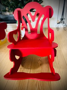 a red rocking chair sitting on top of a wooden floor next to a christmas tree