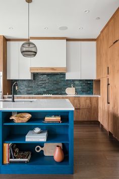 a kitchen with wooden cabinets and blue island in the center, surrounded by white cupboards