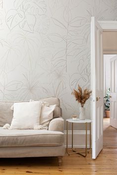 Light and airy living room featuring neutral botanical wallpaper with delicate leaf designs, a cozy beige sofa, soft cushions, and minimal décor for a natural, relaxed feel. Drawings Of Leaves, Warm Neutral Living Room, Tropical Wall Mural, Neutral Living Room Ideas, Soft Living Room, Living Room Styling, Soft Living, Wallpaper Neutral, Cozy Living Room Ideas