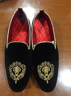 a pair of black shoes with gold lion embroidered on them