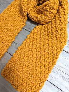 a yellow knitted scarf sitting on top of a wooden floor