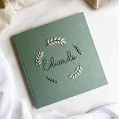 a green book with the word aurora written in cursive writing on it, surrounded by white linens