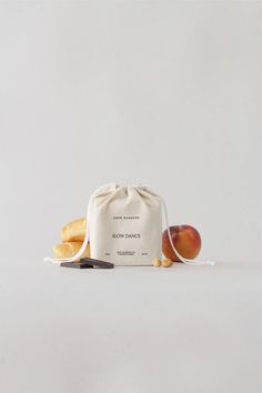 a bag with some bread and an apple on the side next to it, in front of a white background