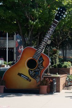 a large guitar statue sitting on the side of a road