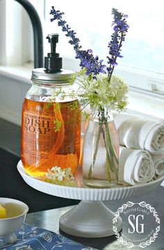 a jar filled with liquid sitting on top of a table next to towels and flowers