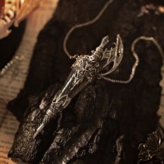 a necklace with a cross on it sitting next to some rocks and other jewelry items