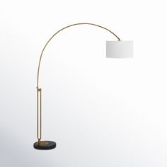 a floor lamp with a white shade on the top and a black base, standing in front of a white wall