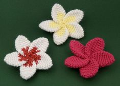 three crocheted flowers on a green surface