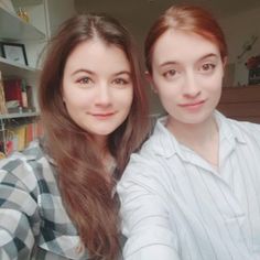 two young women taking a selfie in front of a book shelf with books on it