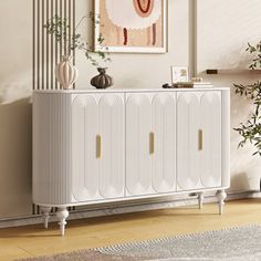 a white cabinet sitting next to a plant in a living room