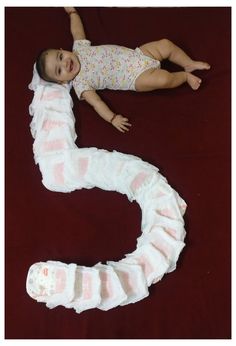 a baby laying on top of a red blanket next to a white and pink snake