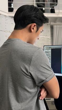 a man standing in front of a computer monitor with his hands on his hips and looking at the screen