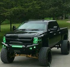 a large black truck with green lights on it's front bumpers and tires