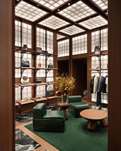 a room filled with lots of green furniture and shelves full of clothes on display behind glass doors