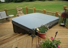 a hot tub sitting on top of a wooden deck next to a potted plant