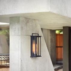 an outdoor wall light mounted on the side of a concrete building with stairs leading up to it