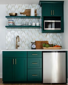 a kitchen with green cabinets and stainless steel dishwasher in the center, on top of a wooden floor