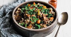 a bowl filled with rice and vegetables on top of a blue cloth next to a spoon