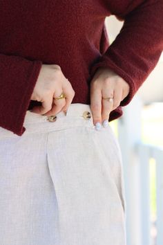 a woman in a red sweater and white pants is holding her hands on the waist