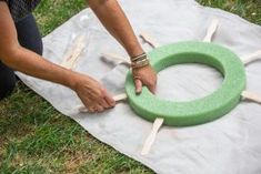 a person is making a wreath out of popsicle sticks on the ground with their hands