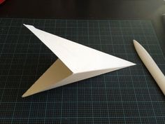 a paper airplane sitting on top of a table next to a pencil