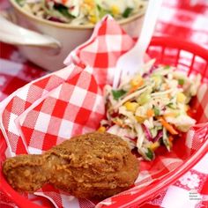 a red basket filled with fried food next to a bowl of coleslaw and salad