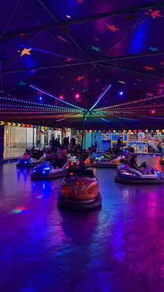 several bumper cars in a brightly lit indoor ride - on area at an amusement park