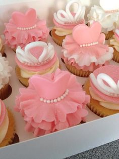 cupcakes decorated with pink and white icing in a box