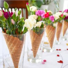 there are many flowers in the ice cream cone vases on the dining room table