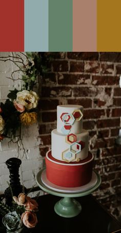 a multi - tiered cake on a table in front of a brick wall