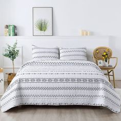 a bed with white and black bedspread in a room next to a chair