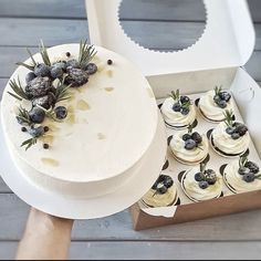 a white cake sitting on top of a table next to cupcakes in a box