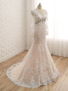 a wedding dress is displayed on a mannequin in front of a brick wall