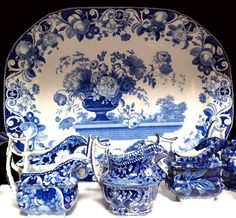 a blue and white china set with flowers on the plate, vases and bowls