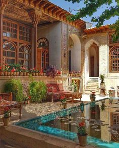 an outdoor patio with potted plants and flowers on the table, next to a pool