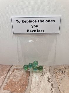 some green beads sitting on the ground in front of a sign that says to replace the ones you have lost