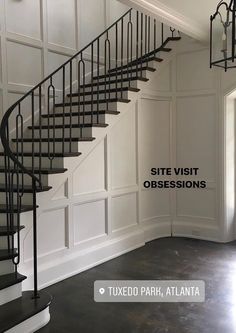 a spiral staircase in an empty room with white walls and black iron railings on either side