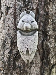 a stone bear ornament hanging on a tree